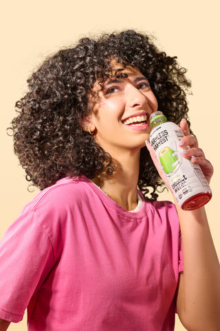 woman holding a bottle of harmless harvest organic coconut water